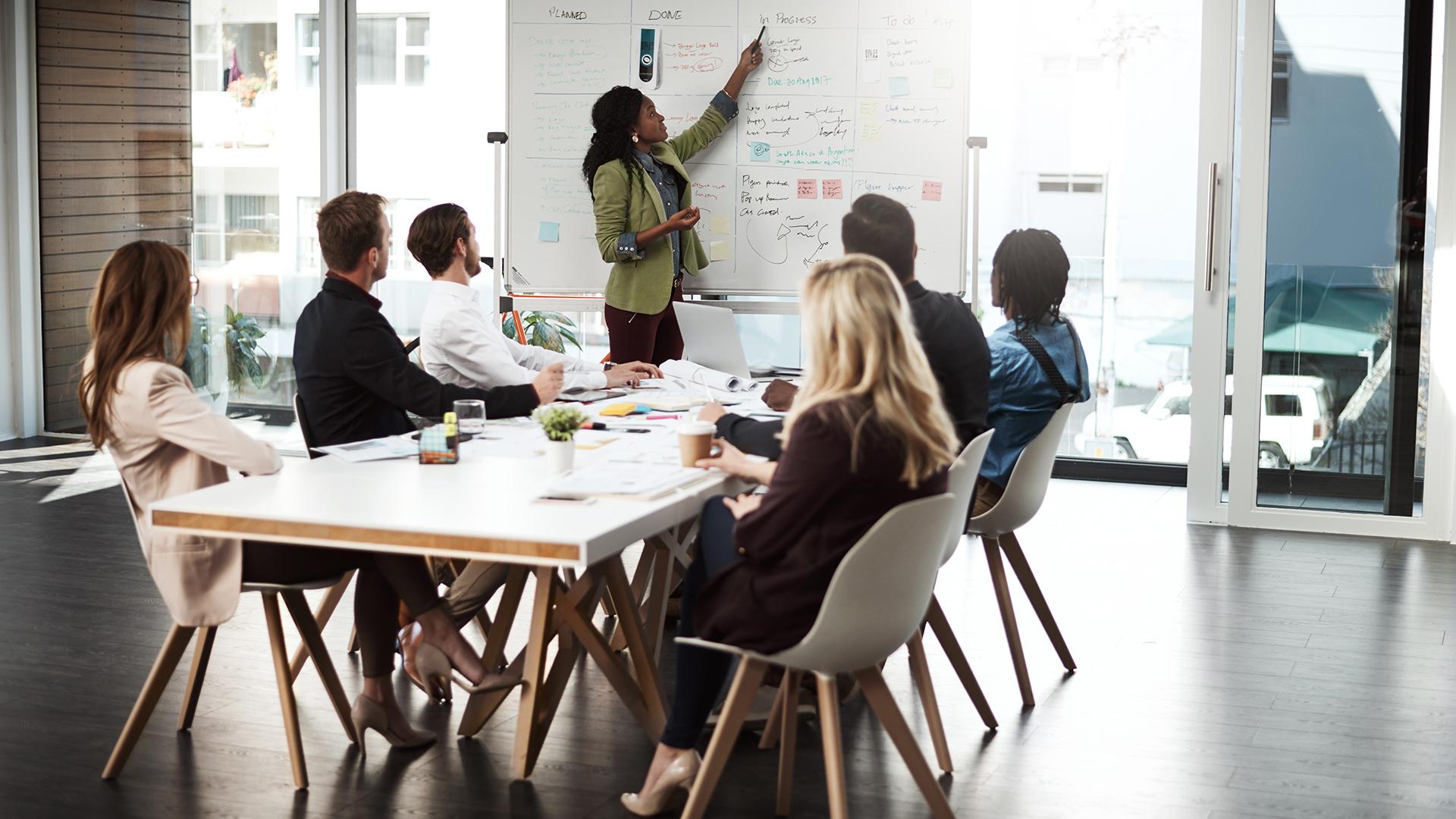 People in a room with a white board and papers.
